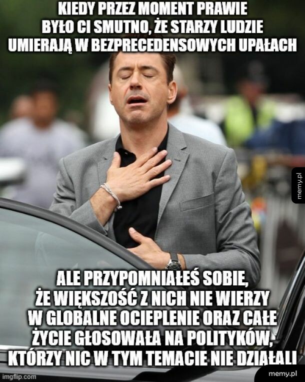 Mężczyzna w garniturze z ręką na sercu, wyrażający emocje.