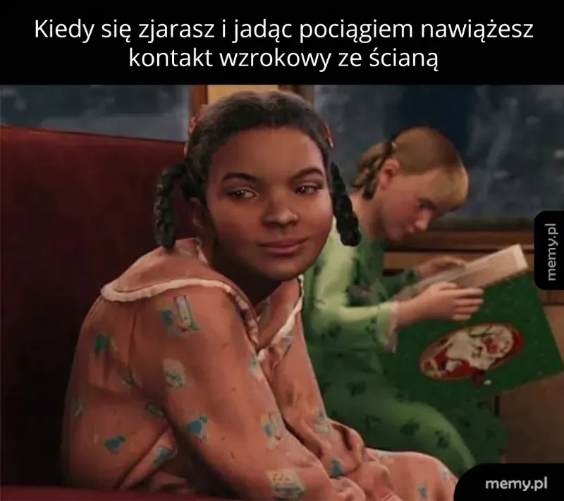 Dziewczyna w piżamie siedzi w pociągu, z uśmiechem patrzy w stronę kamery, obok niej inna dziewczyna czyta książkę.