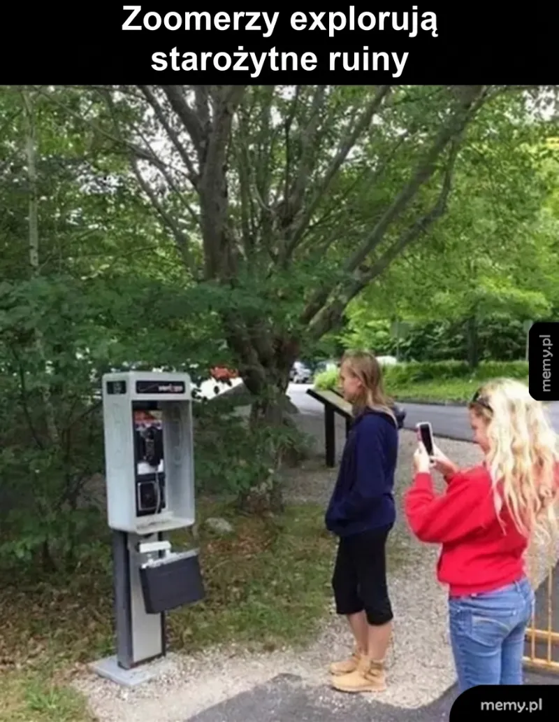 Młode osoby przy starym telefonie publicznym w otoczeniu drzew.