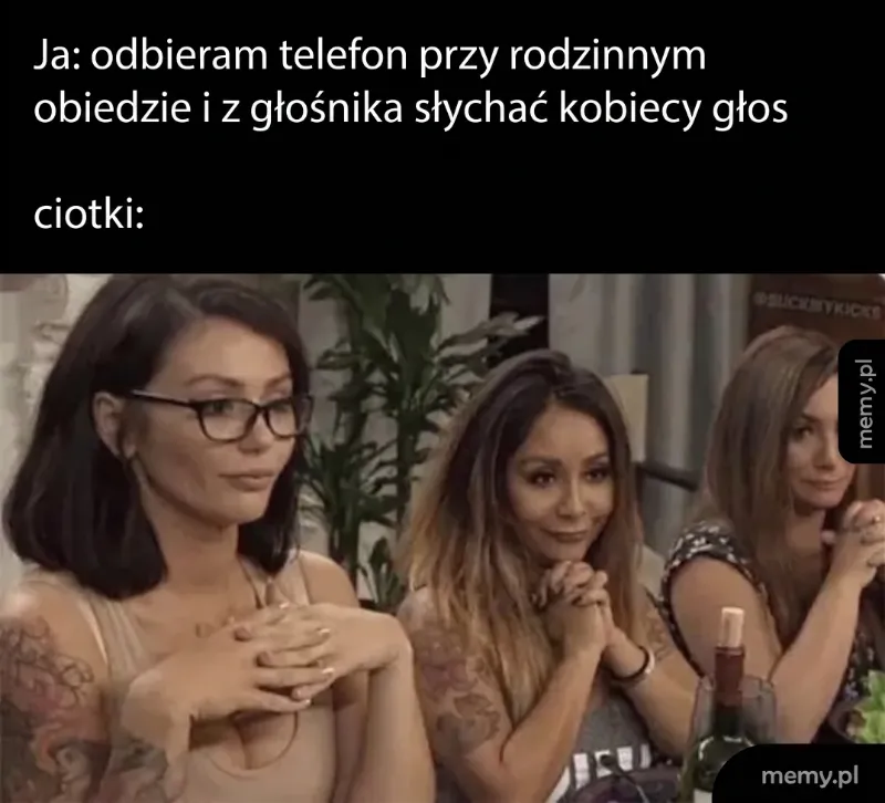 Trzy kobiety siedzą przy stole, jedna z nich ma ręce złożone na stole.