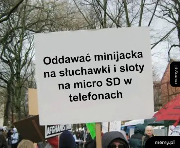 Transparent z napisem na tle ludzi na demonstracji.