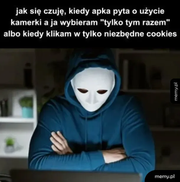 Osoba w masce siedzi przed komputerem, patrząc na ekran.