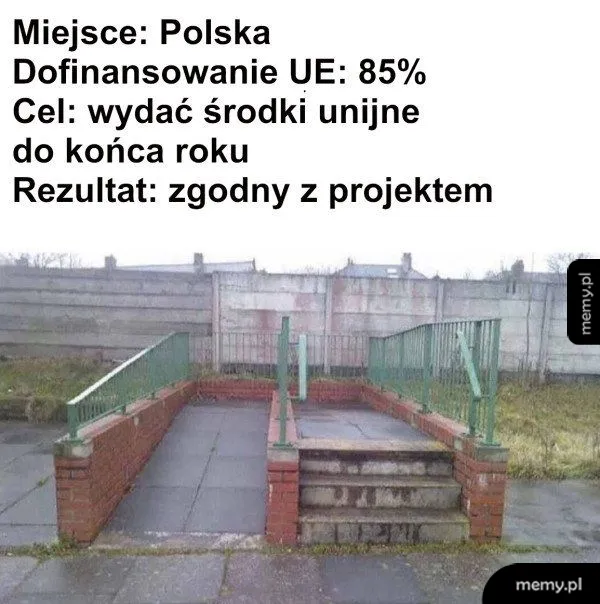 Schody i podjazd prowadzące donikąd przed betonowym płotem.