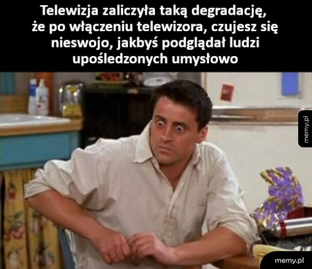 Mężczyzna z wytrzeszczem oczu siedzi w kuchni, mem z serialu Przyjaciele.